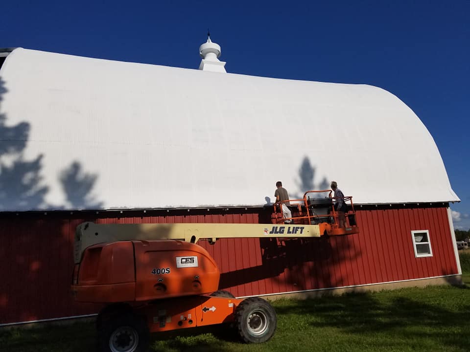 finishing up spray coating on a metal barn roof